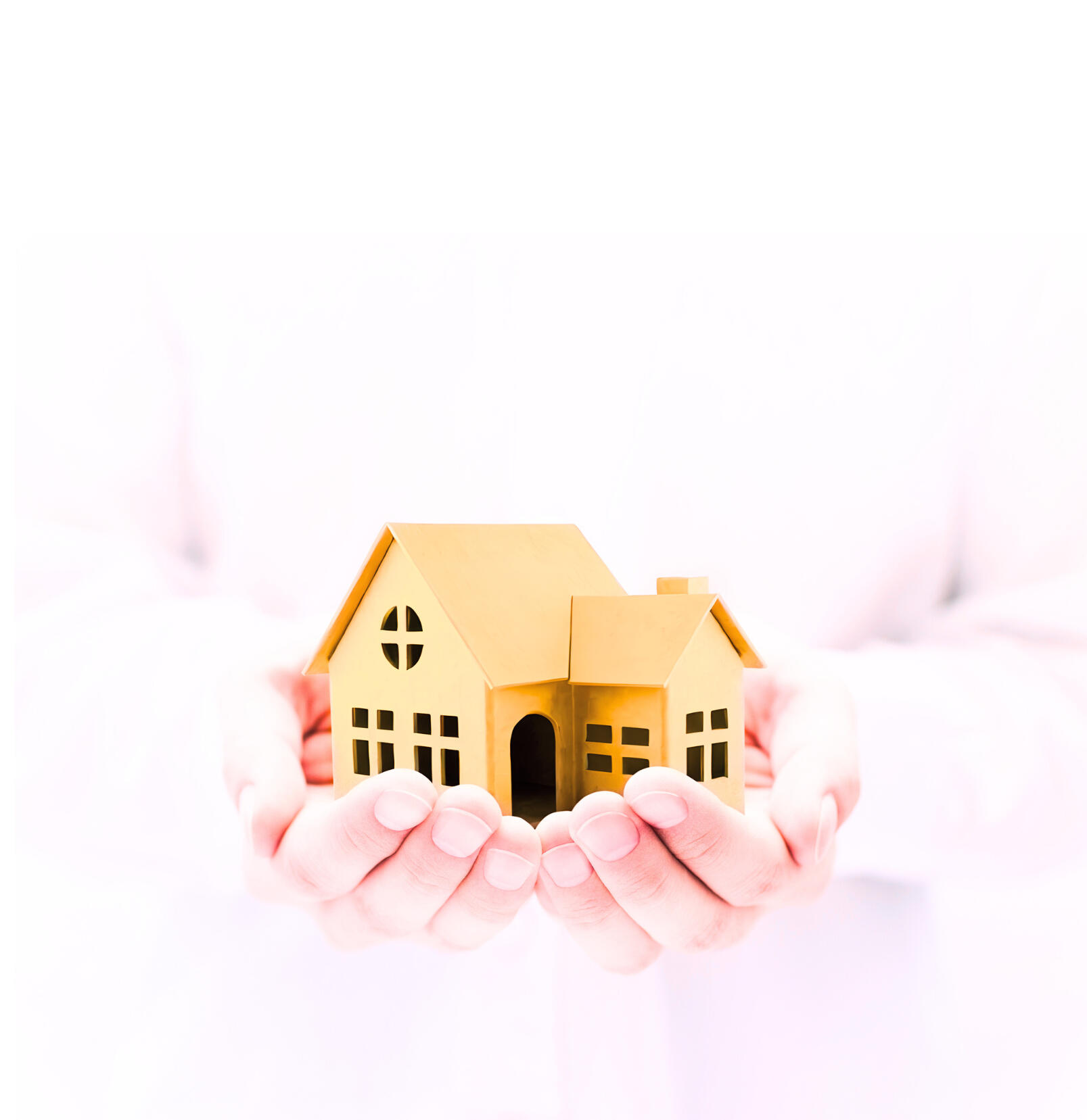 A black and white picture of two hands cupped together, with a small model of a house placed in the centre of the hands held with a caring and gentle nature.